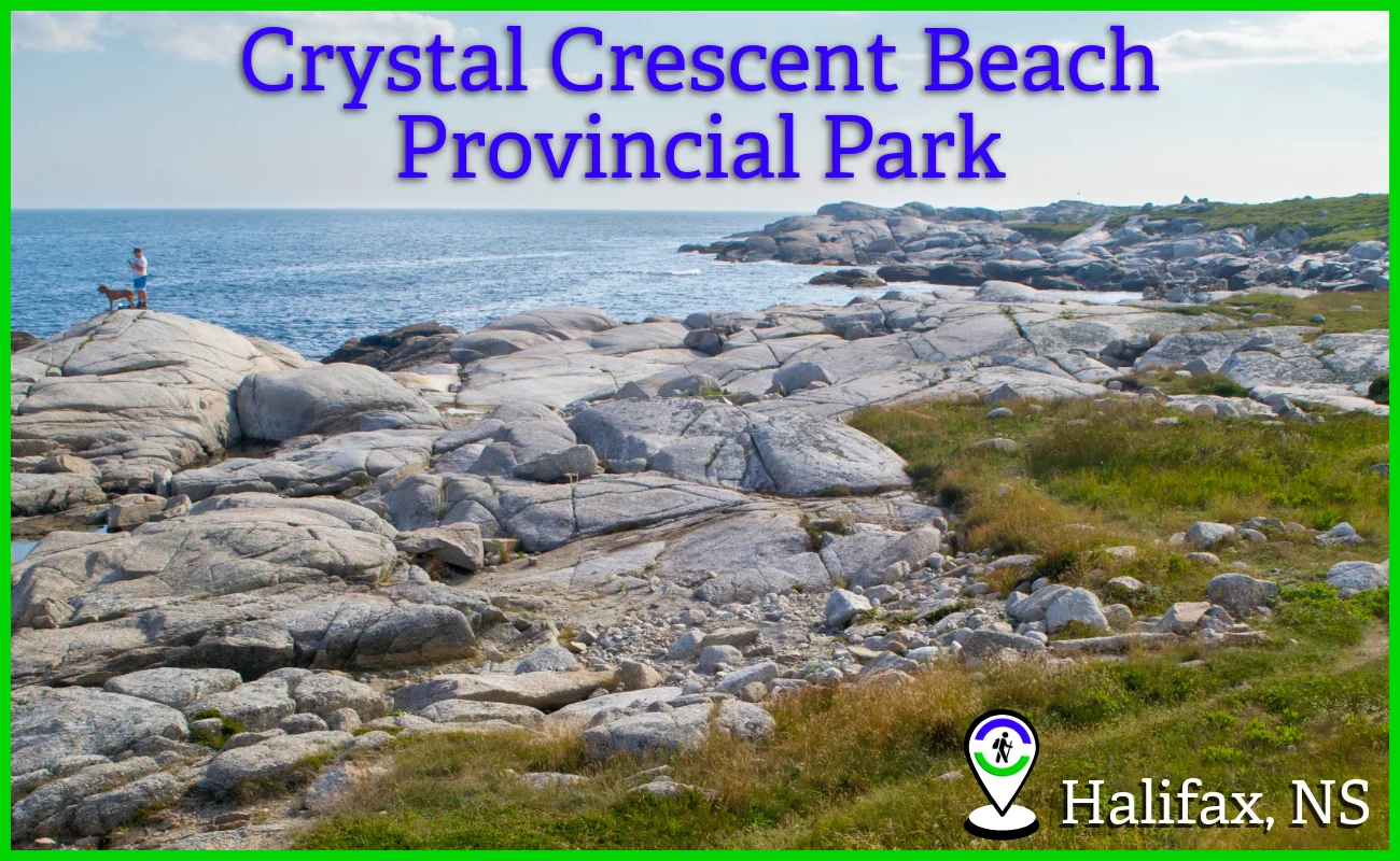 Panoramic view of the rugged granite coastline and coastal hiking trails at Crystal Crescent Beach Provincial Park in Halifax, Nova Scotia, featuring a person and a dog standing on large rocks overlooking the blue Atlantic Ocean.