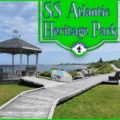 A scenic view of the SS Atlantic Heritage Park in Terence Bay, Nova Scotia, featuring a wooden gazebo, boardwalk, and picnic tables overlooking the ocean under a blue sky.