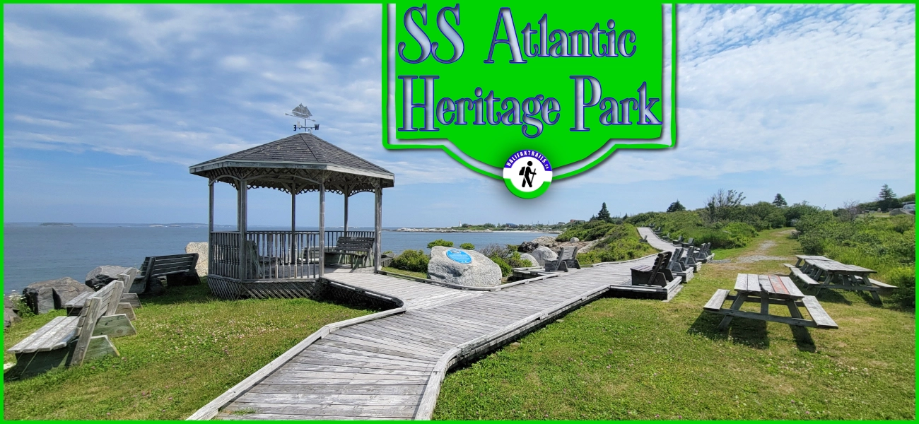 A scenic view of the SS Atlantic Heritage Park in Terence Bay, Nova Scotia, featuring a wooden gazebo, boardwalk, and picnic tables overlooking the ocean under a blue sky.
