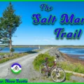 Wide gravel path on the Salt Marsh Trail in Cole Harbour, Nova Scotia, part of the Trans Canada Trail, stretching across calm coastal waters and marshes under a bright sky.