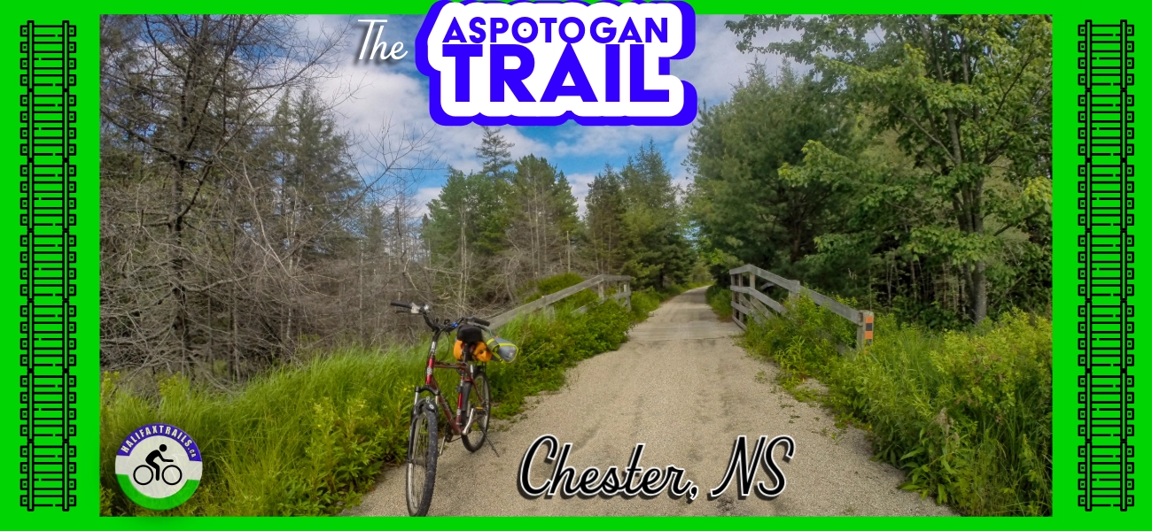 A bicycle parked on a wooden bridge along the Aspotogan Trail in Chester, Nova Scotia, with lush green foliage and blue sky, featuring a title graphic